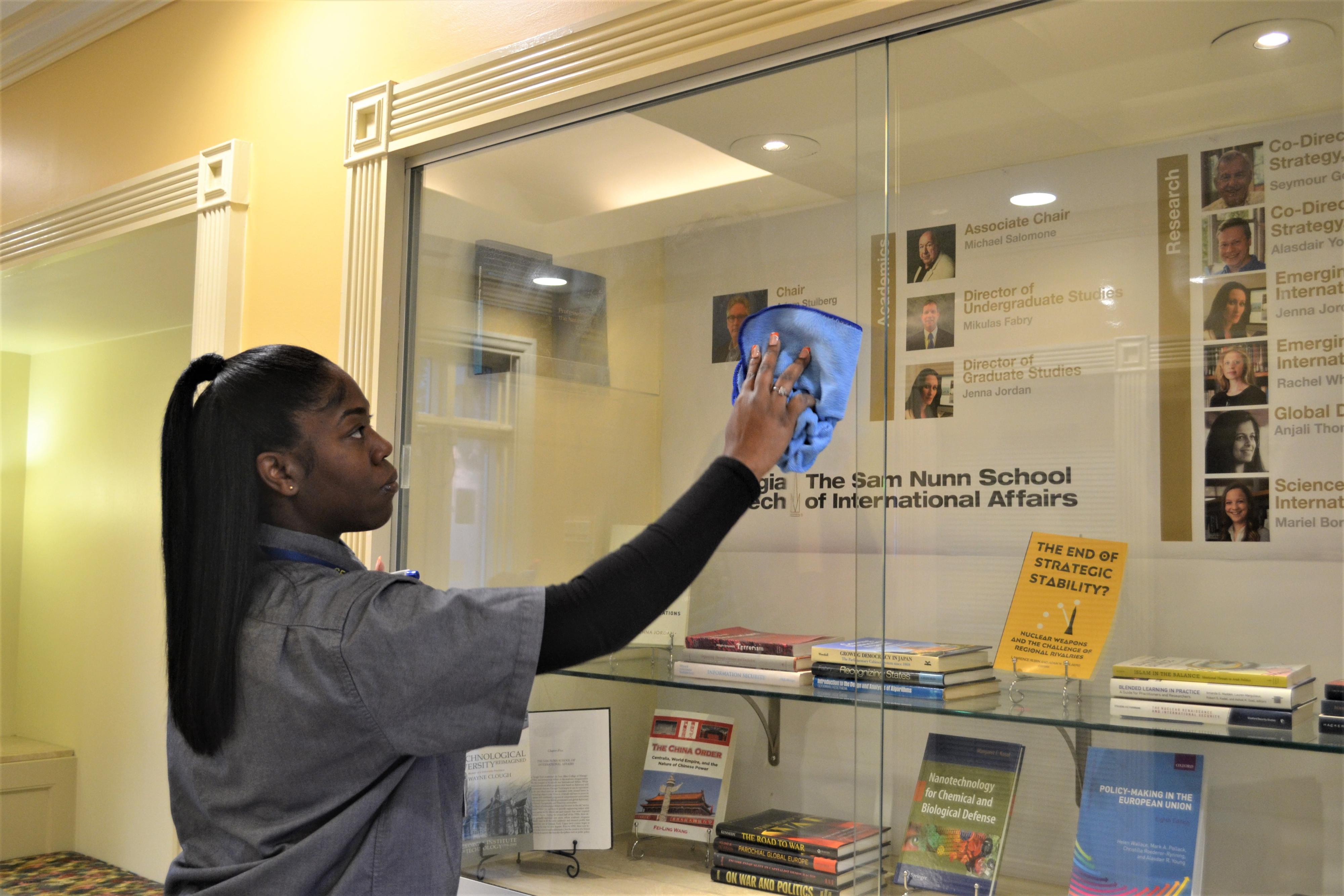 member of the Georgia Tech custodial team cleaning a glass case on campus