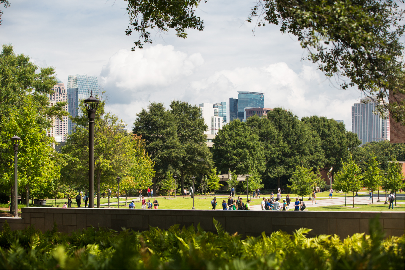 view of campus with a lot of trees in background and students walking in foreground