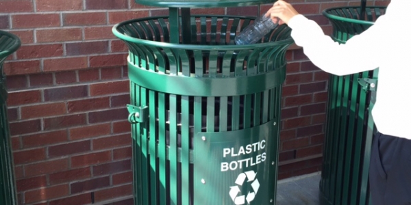Image of a recycling can with a student
